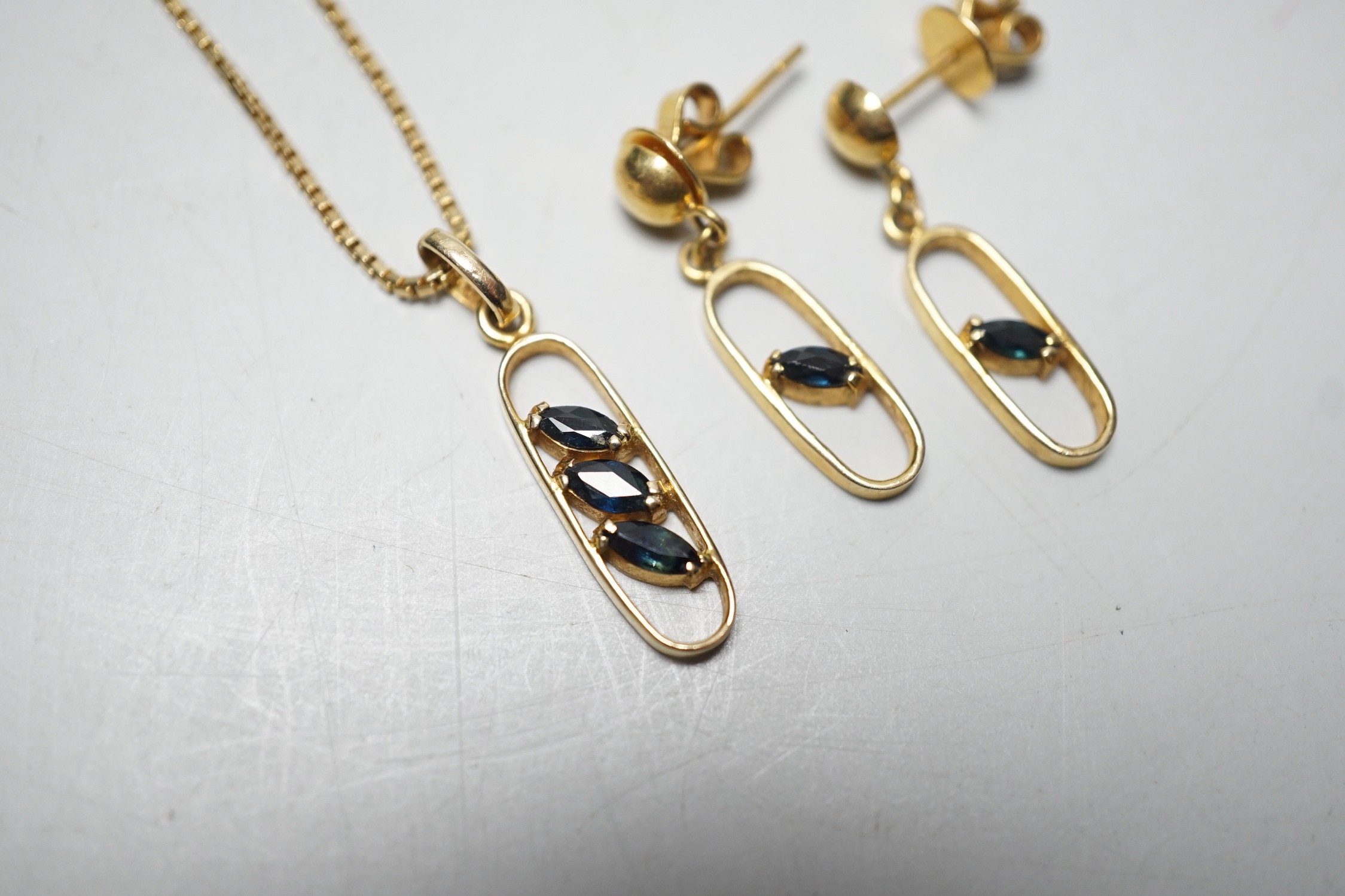 A modern 585 yellow metal and three stone sapphire set pendant necklace, overall 46cm necklace and a pair of matching earrings